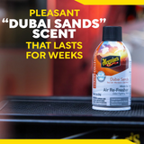 Meguiar's Dubai Sands air freshener bottle on a car dashboard with promotional text.