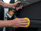 Person cleaning a car door with a yellow sponge and a spray bottle labeled 'Rust-Oleum'.