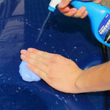 Person washing a car with a blue spray bottle and sponge