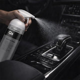 Person using a 'QS Quick & Shine' spray can on a car's gear shift.